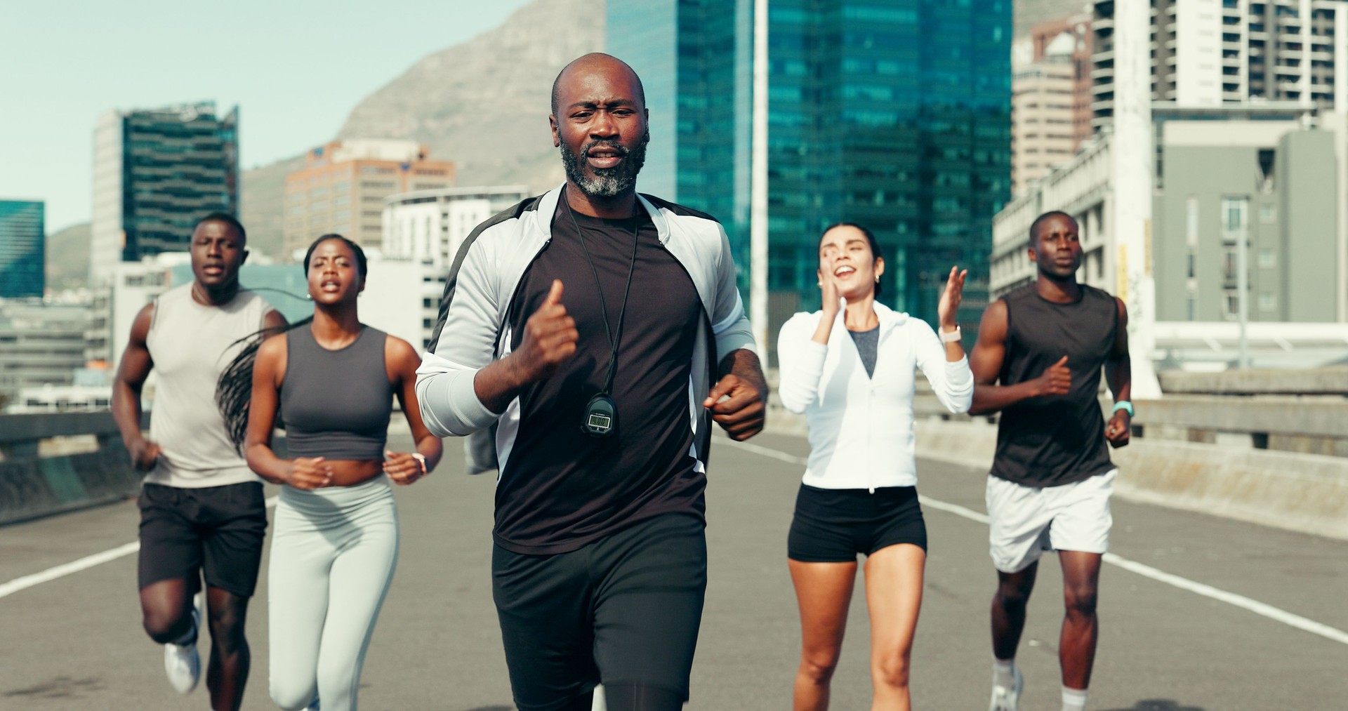 Coach, group and running in city, fitness and motivation for marathon training with speed on bridge. Mentor, people and outdoor on urban street for cardio workout, exercise and challenge in town